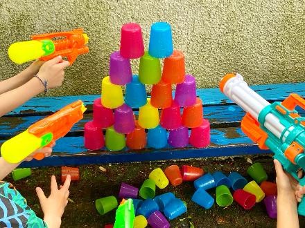 Kinderhände halten Wasserpistolen auf Plastikbecher
